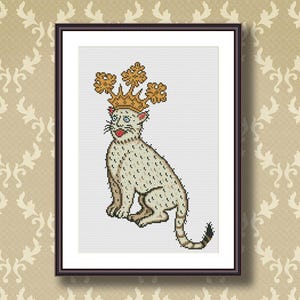 Könnte beinhalten: Gerahmtes Kreuzstich-Kunstwerk mit einer sitzenden Katze, die eine goldene Krone mit floralen Akzenten trägt. Die Katze hat einen hellbeige Körper mit dunklen Flecken, eine rote Zunge und eine schwarze Schwanzspitze. Der Rahmen ist dunkelbraun.