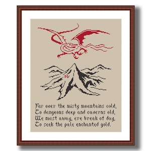 May include: Cross-stitch artwork in a brown frame. The design features a red dragon above a black mountain range. Below, the text reads "Far over the misty mountains cold..." in a classic font.