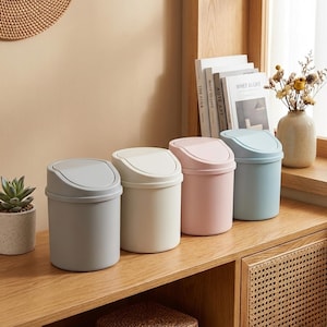 Puede incluir: Cuatro cubos de basura cilíndricos de plástico con tapa basculante, dispuestos en fila. Los cubos son de tonos suaves gris, crema, rosa claro y azul claro, cada uno con un acabado mate liso y un diseño de tapa redondeada.