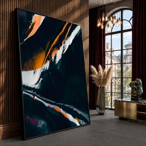 May include: A large rectangular framed wall art piece featuring an abstract composition of deep black, vibrant orange, and stark white fluid strokes. The artwork is displayed in a thin black frame, showcasing bold, sweeping color gradients.