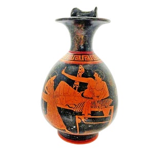May include: A black and red ancient Greek ceramic bottle with a lid. The bottle is decorated with a red and white geometric pattern around the neck and a scene of two figures in red on a black background.