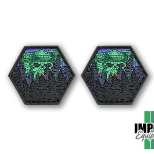 May include: Two black, hexagonal patches featuring a green, stylized skull design with a forest backdrop. The skull has a crown and is surrounded by trees. The patches are likely for clothing or gear.