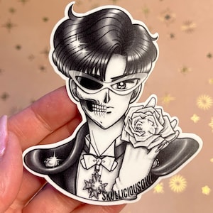 May include: Black and white sticker of a character with a skull face, wearing a tuxedo and holding a rose. The character has a crown on their head and the text "SKULLICIOUS SOUL" is at the bottom of the sticker.