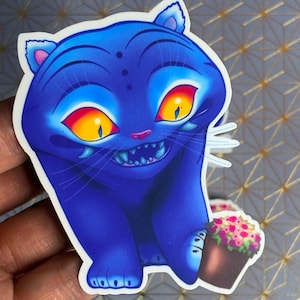 Peut inclure: Autocollant de chat bleu avec un sourire espiègle et des yeux jaunes avec des accents rouges. Le chat tient un petit pot marron avec des fleurs roses et violettes. L'autocollant a une bordure blanche et un style de dessin animé.
