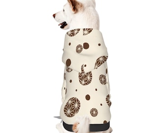 Puede incluir: Una sudadera con capucha para perro de color crema con un patrón repetitivo de diseños geométricos circulares marrones y puntos marrones sólidos. La prenda incluye una capucha y un dobladillo negro sólido en la parte inferior.