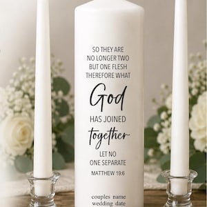 May include: A large white pillar candle featuring the black printed text: SO THEY ARE NO LONGER TWO BUT ONE FLESH THEREFORE WHAT God HAS JOINED together LET NO ONE SEPARATE MATTHEW 19:6, followed by placeholders for couples name and wedding date.