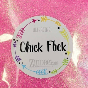 May include: Pink ultra fine glitter with a white circle label that says "Ultrafine Chick Flick Zinbee.com" with arrows around the edge.