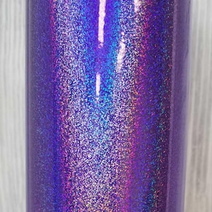 Op de afbeelding: Een close-up van een paarse tumbler met iriserende glitter. De glitter heeft een regenboog effect, met tinten roze, blauw en groen.