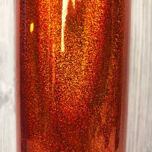 May include: Close-up of a copper-colored glitter tumbler. The glitter is fine and creates a shimmering effect.