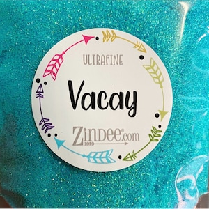 May include: A close-up of a turquoise glitter with a white label that says "Ultrafine Vacay Zindee.com" with arrows around the edge.