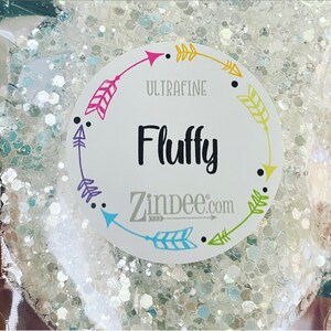 May include: A white glitter jar with a round label that says "Ultrafine Fluffy Zindee.com" with colorful arrows around the border.
