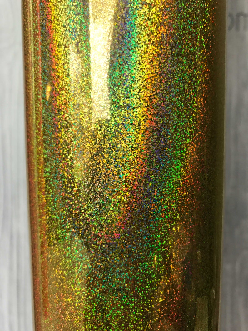 May include: A close-up of a gold iridescent glitter vinyl sheet. The glitter is fine and creates a shimmering effect.