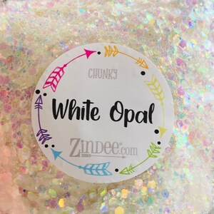 May include: White Opal chunky glitter with iridescent shimmer. The glitter is packaged in a clear jar with a white label that says "White Opal" and "Zindee.com".