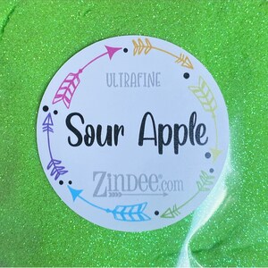 May include: A green glitter with a white circle label that says "Ultrafine Sour Apple Zindee.com" with arrows around the label.
