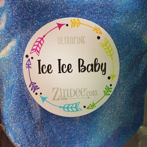 May include: A close-up of a blue glitter jar with a white label. The label has a circle of colorful arrows around the text "Ultrafine Ice Ice Baby" and the website "Zindee.com".