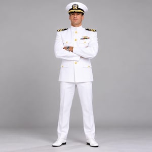Könnte beinhalten: Eine weiße Dienstuniform der US Navy, bestehend aus einer Jacke mit Stehkragen und goldenen Knöpfen, einer passenden weißen Hose, einer weißen Schirmmütze mit goldenem Emblem und weißen Schuhen, getragen mit Schulterklappen und Orden.