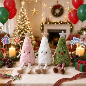 May include: Three plush cone-shaped figures with star toppers, sitting on a table. The left is pink, the center is white, and the right is green. Each has dangling striped legs, small arms, and black eyes. Signs reading "Birge's" and "Hekco" are nearby.