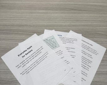 May include: A stack of white printed paper sheets titled Everyday Apps for Seniors, featuring instructional text about smartphone applications for rides, shopping, groceries, and weather, with page numbers visible at the bottom corners.