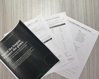 May include: A stack of printed documents featuring a black cover page with the white text Build the league. Protect the game. and additional pages containing tables, checklists, and planning information for organizing a poker league.
