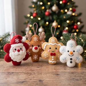 May include: Four knitted holiday ornaments shaped like stars, featuring a Santa Claus, a reindeer, a gingerbread person, and a snowman. Each ornament has a red and white striped hanging loop and is decorated with embroidered snowflake details.