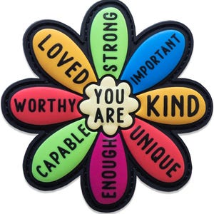 May include: A flower-shaped patch with a cream center reading YOU ARE. The eight colorful petals feature black text: LOVED, STRONG, IMPORTANT, KIND, UNIQUE, ENOUGH, CAPABLE, and WORTHY. The design is outlined in black with a raised, rubberized texture.