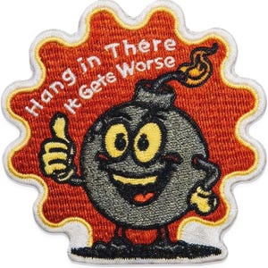May include: An embroidered patch featuring a cartoon bomb character with a smiling face, yellow eyes, and a thumbs-up gesture. The background is a textured orange burst shape with white text that reads Hang in There It Gets Worse.