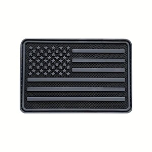 May include: A rectangular patch featuring a monochromatic dark gray American flag design. The flag consists of raised stars and horizontal stripes set against a textured black background, all enclosed within a raised border frame.