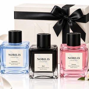 May include: Three square glass bottles of Nobilis Collection home fragrance system, each with a black cap and a label reading Santorini, Bali, or Verona. The bottles contain blue, black, and pink liquid, each holding 16.9 fl oz.