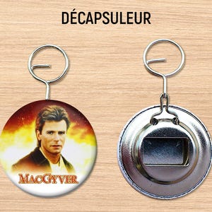 Peut inclure: Un ouvre-bouteille en forme de porte-clés argenté avec une image ronde et colorée d'un homme avec le texte "MacGyver" dessus.