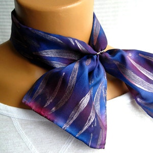 May include: A blue and purple silk scarf with a silver leaf pattern. The scarf is tied around a mannequin's neck.