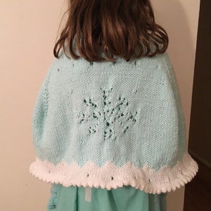 Peut inclure: Un châle en tricot bleu clair avec une bordure en crochet blanc et un motif de flocon de neige au dos.
