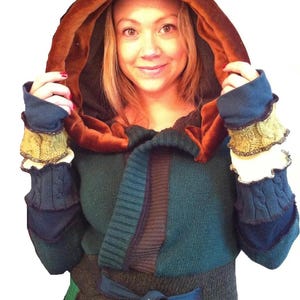 May include: A teal, brown and green patchwork sweater with a brown velvet hood and matching cuffs. The sweater has a tie belt and a cable knit pattern on the sleeves.