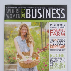 May include: A magazine cover featuring a woman holding a basket of produce. The magazine is titled "Where Women Create Business: A Passion for Success". The cover also features articles about Lylah Ledner, Kathy Davis, and Ruche.