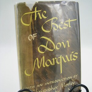 May include: A vintage hardcover book titled "The Best of Don Marquis" with an introduction by Christopher Morley. The book is displayed on a black metal book stand.