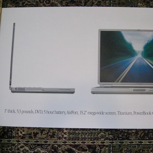 May include: An advertisement for a silver PowerBook G4 laptop, showcasing a side and front view. The screen displays a road scene. Text includes "1" thick, 53 pounds, 15.2" mega-wide screen, and "Think different."