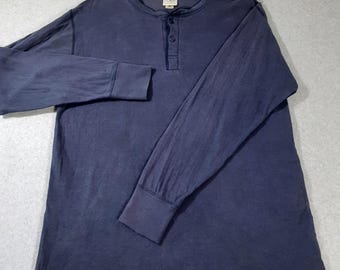 May include: A long-sleeve navy blue henley shirt featuring a three-button placket at the neckline and ribbed cuffs. The interior collar tag displays the L.L.Bean brand name. The fabric has a slightly faded, worn-in appearance throughout.