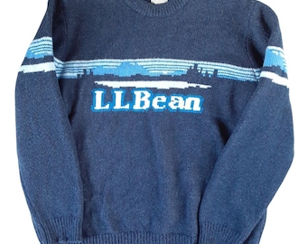 May include: A navy blue long-sleeve crewneck sweater featuring a horizontal band across the chest with a light blue and white mountain landscape graphic and the text LLBean in white and blue lettering on the front of the garment.
