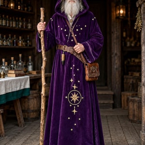 May include: A floor-length purple velvet hooded robe featuring gold embroidered star patterns and a central celestial motif. The garment is worn with a brown leather belt, a matching leather satchel, and a wooden staff held in one hand.