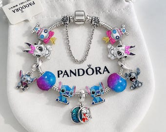 May include: A silver Pandora charm bracelet featuring multiple character charms including Stitch and Angel, colorful gradient beads, and a safety chain. The bracelet is displayed on a white fabric pouch with the Pandora logo printed in black.