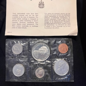 Può includere: Un foglio di plastica trasparente con sette monete canadesi in scomparti individuali. Le monete sono una moneta canadese da 50 centesimi del 1967, una moneta canadese da 25 centesimi del 1967, una moneta canadese da 10 centesimi del 1967, una moneta canadese da 5 centesimi del 1967, una moneta canadese da 1 centesimo del 1967, una moneta canadese da 5 centesimi del 1967 e una moneta canadese da 1 centesimo del 1967. Tutte le monete sono non circolanti e in ottime condizioni.