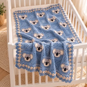 May include: A blue crochet blanket featuring a repeating pattern of koala faces in each square. The blanket has a decorative scalloped border in a light beige color and is draped over the side of a white wooden crib frame.