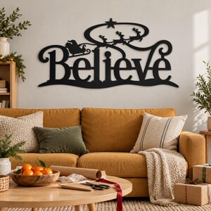 May include: A black metal wall sign featuring the word Believe in a decorative script font. Above the text is a silhouette of Santa Claus in a sleigh pulled by reindeer flying toward a star. The design is a single continuous piece.