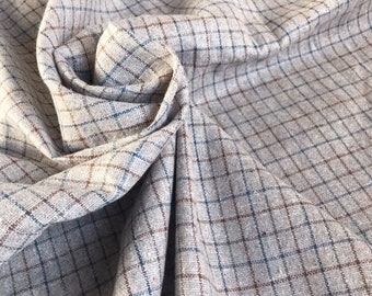 May include: A close-up of a gray and white checkered fabric with brown and blue stripes. The fabric is folded and draped, showing the texture and pattern.