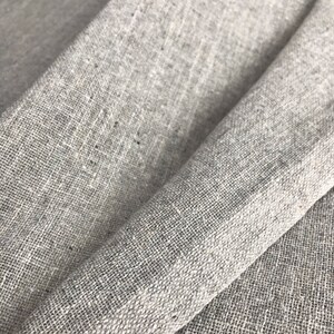 Könnte beinhalten: Nahaufnahme eines hellgrauen Leinenstoffs mit einer strukturierten Webart. Der Stoff ist in der Mitte gefaltet und zeigt die Textur und Farbe des Materials.