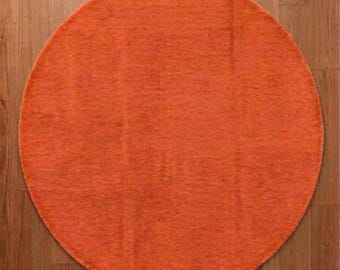 May include: A circular rug in a solid, vibrant orange hue with a textured, short-pile surface. The rug features a subtle, tonal variation in the orange fibers, creating a consistent appearance across the entire round shape.