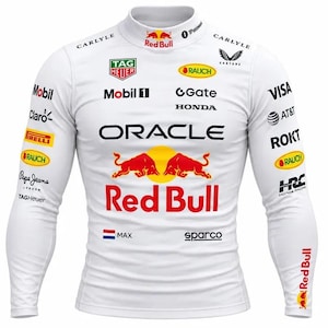 Puede incluir: Una camiseta blanca de manga larga con cuello alto que presenta la marca Red Bull, el logotipo de Oracle y varios logotipos de patrocinadores, incluidos Tag Heuer, Mobil 1, Honda y Pirelli. El pecho muestra dos toros rojos y el texto Max con una bandera holandesa.