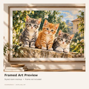 May include: A framed art print featuring three kittens sitting on a stone wall. The center kitten is orange tabby, while the two kittens on the sides are gray tabby. The background shows a garden with white flowers, green foliage, and a building.