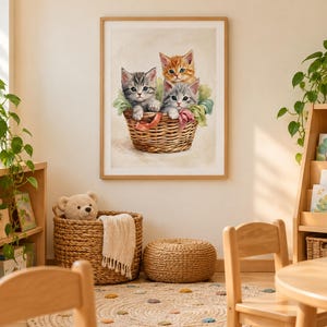 May include: A framed wall art print featuring three kittens sitting inside a woven wicker basket. One kitten is orange tabby, while the other two are gray tabby, all nestled together with soft green fabric accents against a light background.