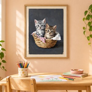 May include: A framed wall art print featuring two tabby kittens sitting inside a woven wicker basket. One kitten is gray and white, while the other is brown and black. The kittens are nestled on a white and pink checkered cloth against a dark background.