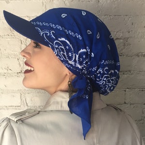 May include: A royal blue bandana with a white paisley pattern is tied around a person's head and styled into a cap with a visor.